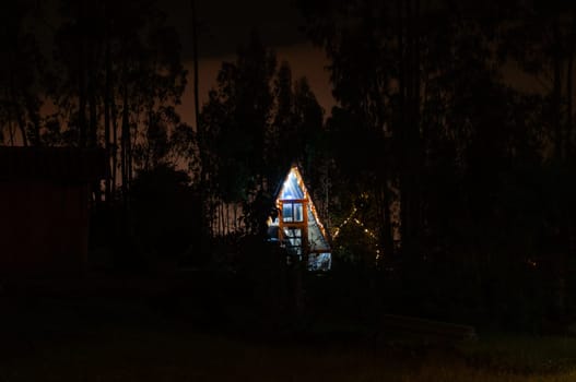 an illuminated glamping house in the middle of a forest at night in total darkness. High quality photo