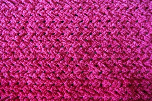 Textures of this close-up of a pink crocheted blanket.