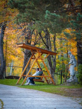 Romantic walk with a couple in the center of an autumn park with bright colors of foliage