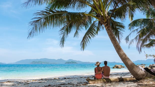 Koh Wai Island Trat Thailand is a tinny tropical Island near Koh Chang. a young couple of men and women on a tropical beach during a luxury vacation in Thailand, couple sitting under a palm tree