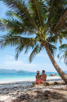 Koh Wai Island Trat Thailand near Koh Chang. a young couple of men and women on a tropical beach during a luxury vacation in Thailand, men and woman relaxing under a palm tree at a natural beach