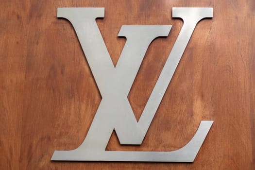 4 May 2023 Paris, France. Close up of Louis Vuitton signature brand logo in brushed chrome on a wood paneled wall. Louis Vuitton has stood for quality, luxury and fashion since 1854. High quality photo