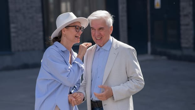 Stylish elderly laughing couple on a walk. Romantic relationships of mature people