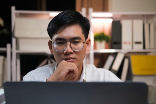 Young Asian businessman working tired office worker sitting at desk using computer and doing overtime project.