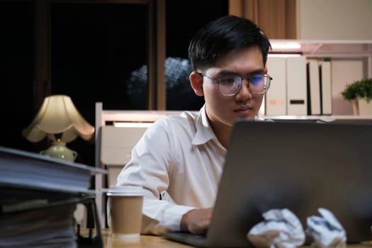Young Asian businessman working tired office worker sitting at desk using computer and doing overtime project.
