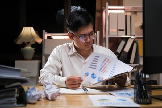 Young Asian businessman working tired office worker sitting at desk using computer and doing overtime project.