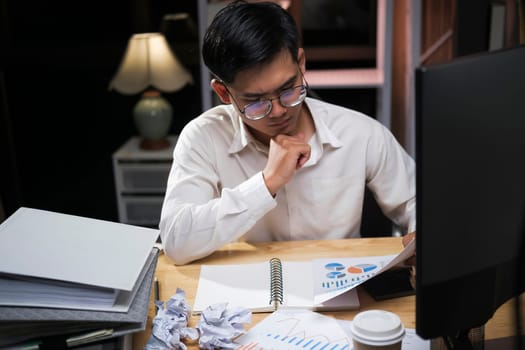 Young Asian businessman working tired office worker sitting at desk using computer and doing overtime project.