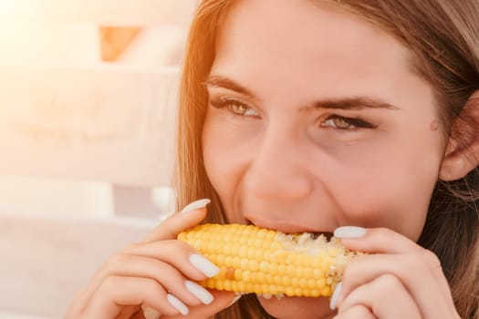 Healthy vegetarian hipster woman in summer outfit eat grilled corn and look to camera. Sexy lady on sea beach sunset or ocean sunrise. Travel, explore, active yoga and meditation lifestyle concept.