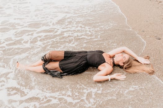 Woman travel sea. Young Happy woman in a long red dress posing on a beach near the sea on background of volcanic rocks, like in Iceland, sharing travel adventure journey