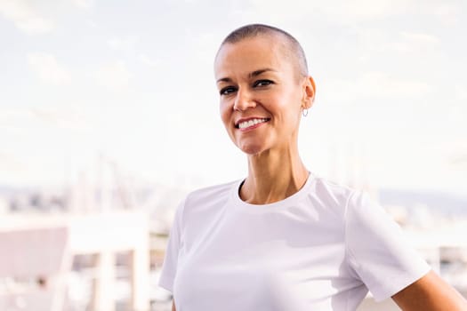 portrait of a woman with shaved head smiling happy looking at camera, concept of happiness and confidence