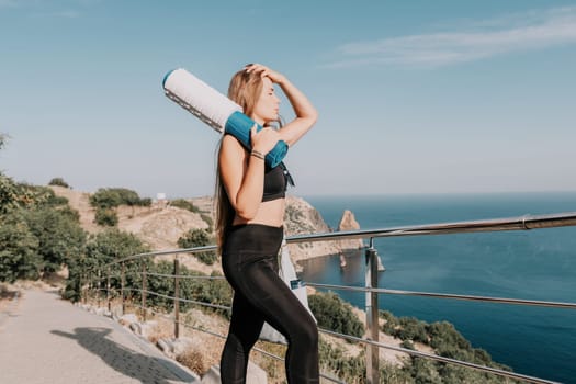 Fitness woman sea. Outdoor workout on yoga mat in park near to ocean beach. Female fitness pilates yoga routine concept. Healthy lifestyle. Happy fit woman exercising with rubber band in park.