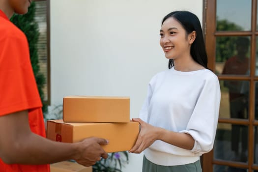 Young Asian cute girl receiving boxes from postman at the door. Delivery concept.