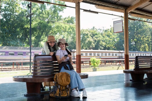 Asian woman friends at railway station have happy moment. Tourism and travel.