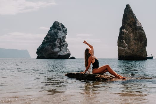 Woman travel sea. Young Happy woman in a long red dress posing on a beach near the sea on background of volcanic rocks, like in Iceland, sharing travel adventure journey