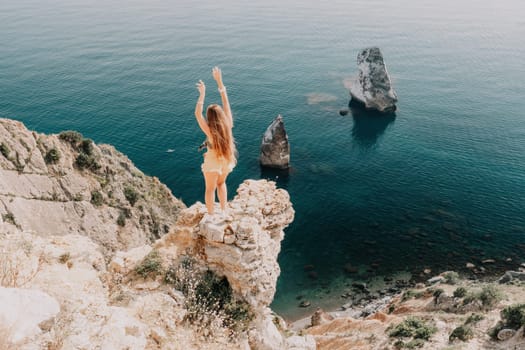 Woman travel sea. Happy tourist taking picture outdoors for memories. Woman traveler looks at the edge of the cliff on the sea bay of mountains, sharing travel adventure journey.