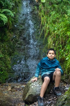 In the heart of nature, an Indian boy seated on a timeless stone.