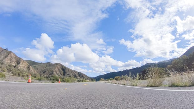 Vehicle is cruising along the Cuyama Highway under the bright sun. The surrounding landscape is illuminated by the radiant sunshine, creating a picturesque and inviting scene as the car travels through this captivating area.