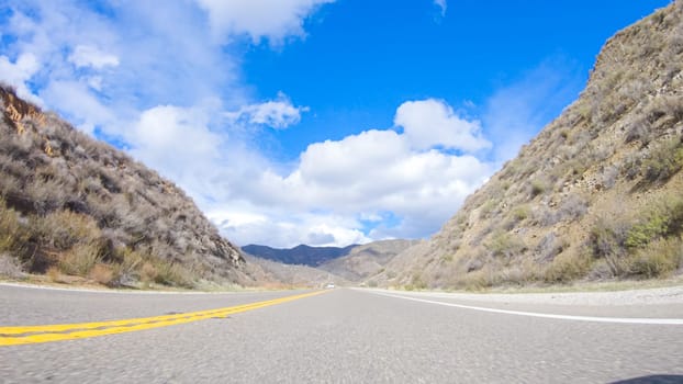 Vehicle is cruising along the Cuyama Highway under the bright sun. The surrounding landscape is illuminated by the radiant sunshine, creating a picturesque and inviting scene as the car travels through this captivating area.