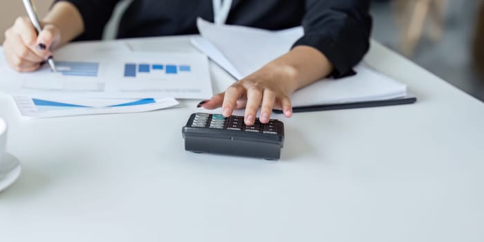 Businesswoman working with document and using calculator for checking finance report.