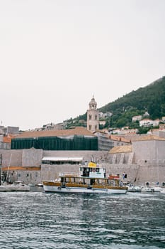 Yacht sails on the sea past the old high fortress wall of Dubrovnik. Croatia. High quality photo