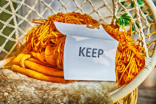 Signs with the words keep, donate, discard and fashion clothes folded in stacks in cozy room. The concept of cluttering and decluttering. Background