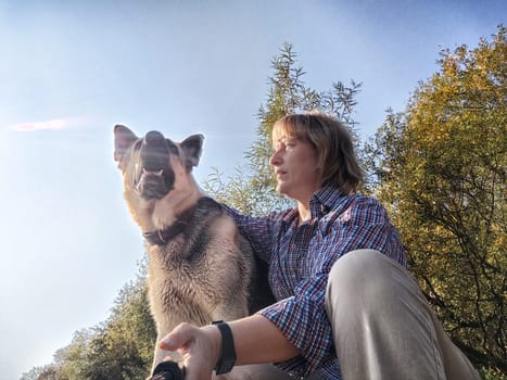 Adult girl with shepherd dog taking selfies in forest. Middle aged woman and big shepherd dog on nature. Friendship, love, communication, fun, hugs