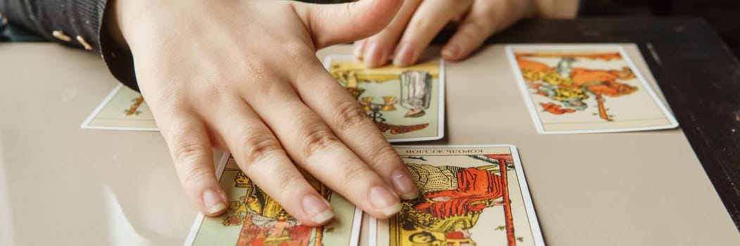 TVER, RUSSIA - FEBRUARY 11, 2023. Tarot cards, Tarot card divination, esoteric background. A woman makes a layout on the cards at the table. Divination, predictions on tarot cards