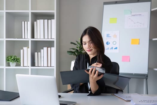 Business documents, business auditor Asian woman is reviewing legal documents, preparing documents or reports for analysis tax accountant documents agreement contract information in office at work.