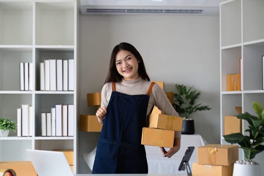 Startup small business entrepreneur SME, asian woman packing cloth in box. Portrait young Asian small business owner home office, online sell marketing delivery, SME e-commerce telemarketing concept.