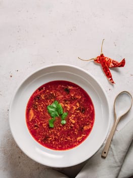 Traditional red soup borscht made with beetroot. National Russian and Ukrainian soup, kitchen, food. Tasty beetroot soup with greens in bowl on neutral pastel background. Top view, flat lay