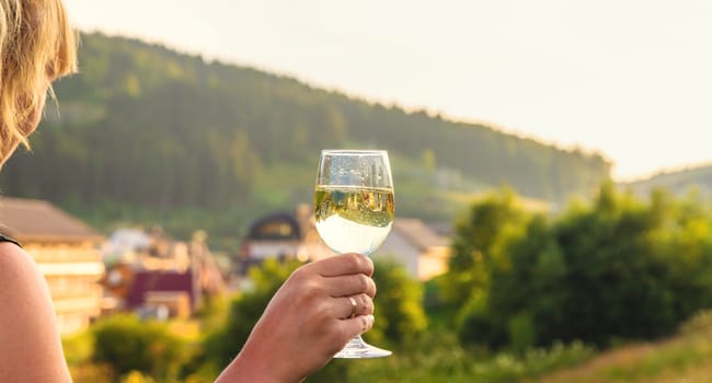 A woman drinks wine against the backdrop of mountains. Selective focus. travel.