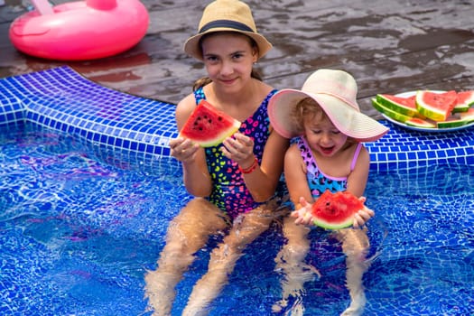 Children eat watermelon near the pool. Selective focus. Food.