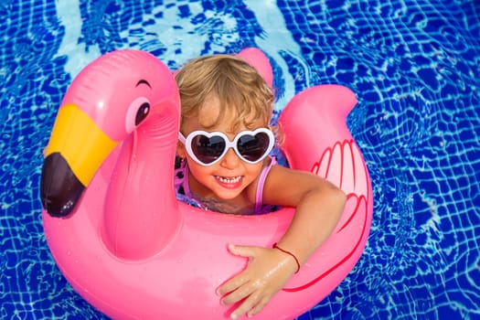 A child swims in a pool in a circle of flamingos. Selective focus. Kid.