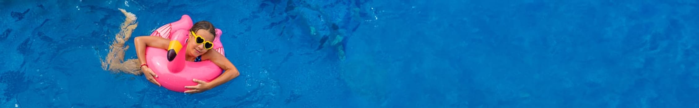 A child swims in a pool in a circle of flamingos. Selective focus. Kid.