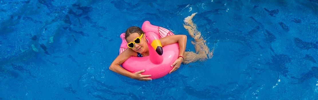 A child swims in a pool in a circle of flamingos. Selective focus. Kid.