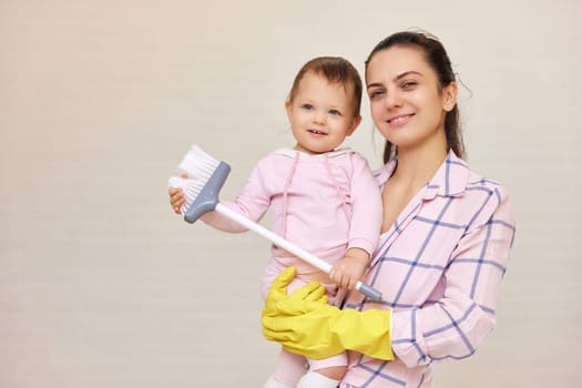 smiling mother housewife is holding cute baby kid and doing housework at home, Happy family, copy space