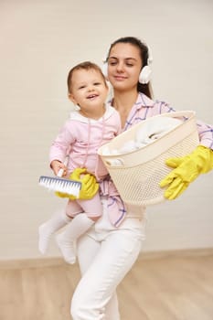 happy mother housewife is holding cute baby girl and basket with laundry , Happy family