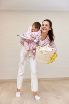 happy mother housewife is holding cute baby girl and basket with laundry , Happy family having fun