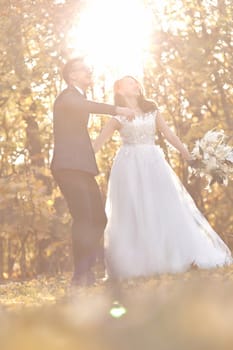 beautiful wedding couple standing outdoor on natural background in sunny day