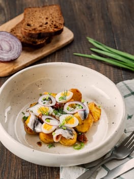 Anchovy or sprat or sardine with potatoes in restaurant-style plating, served onion and greenery. Fish dish, comfort food, authentic kitchen