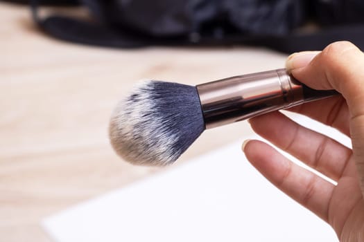 Makeup brushes in hand close up on gray background