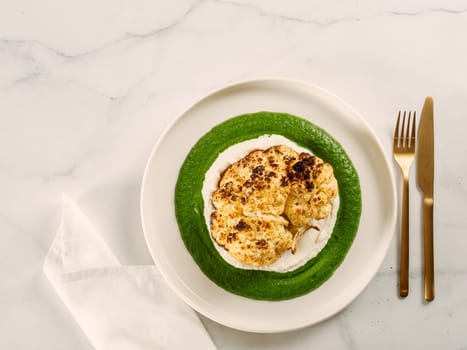 Cauliflower steak with green and white puree. Grilled cauliflower as vegan and vegetarian food concept. Healthy food ideas and menu. Copy space for text