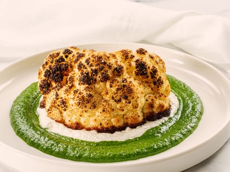 Cauliflower steak with green and white puree. Grilled cauliflower as vegan and vegetarian food concept. Healthy food ideas and menu.