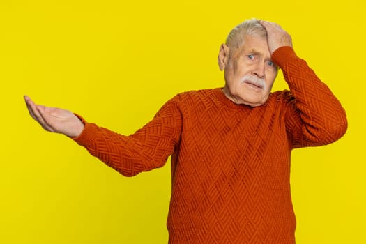 Sad senior old man feeling hopelessness loneliness, nervous breakdown, loses becoming surprised by lottery results, bad fortune, loss unlucky news. Mature grandfather isolated on yellow background