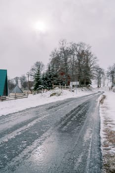 Icy road in a snowy village with cozy houses. High quality photo