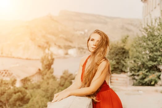 Woman red dress. Summer lifestyle of a happy woman posing near a fence with balusters over the sea