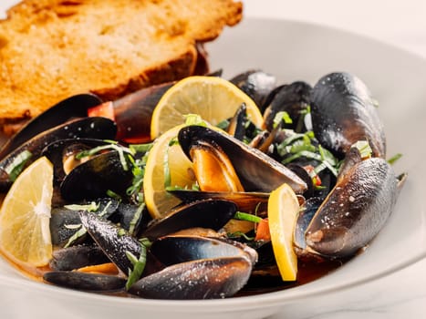 cooked mussels with lemon on white plate. Restaurant-style seafood plating. Seafood and mossels food background