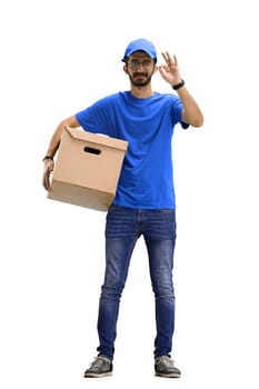 A male deliveryman, on a white background, in full height, shows an ok sign.