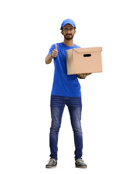 A male deliveryman, on a white background, in full height, with a box, shows a thumbs up.