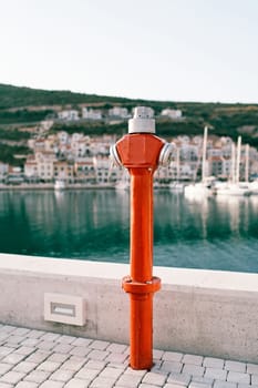 Red fire hydrant stands on a pier by the sea. High quality photo